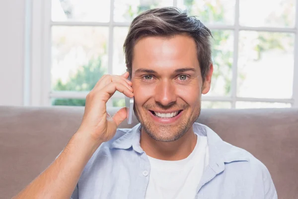 Close-up of a casual man using mobile phone on sofa — Stock Photo, Image