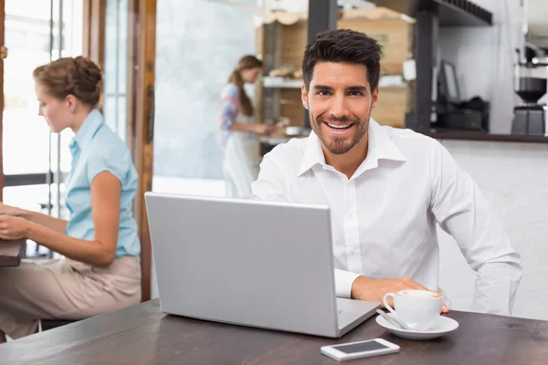 Hombre sonriente usando portátil en la cafetería — Foto de Stock