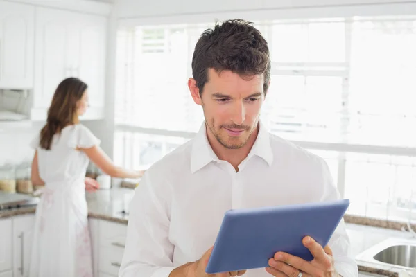 Man using digital tablet with woman in background at kitchen — Stock Photo, Image