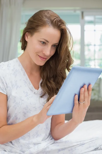 Piękna kobieta uśmiechający się za pomocą cyfrowego tabletu w łóżku — Zdjęcie stockowe