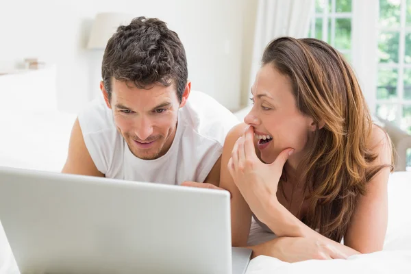 Happy couple using laptop in bed — Stock Photo, Image