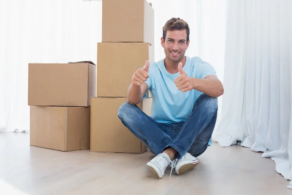 Man gebaren duimen omhoog met kartonnen dozen in nieuwe huis — Stockfoto