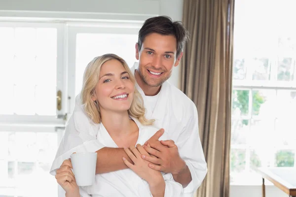 Loving man embracing woman from behind at home — Stock Photo, Image