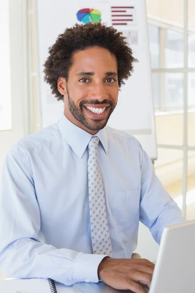 Uomo d'affari sorridente utilizzando il computer portatile alla scrivania dell'ufficio — Foto Stock