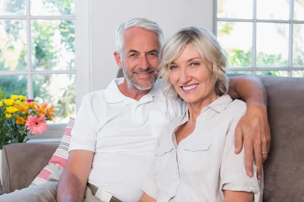 Smiling mature couple sitting on sofa in living room — Stock Photo, Image