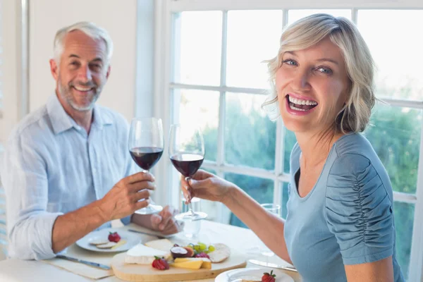 Portret van een volwassen paar roosteren wijnglazen over voedsel — Stockfoto