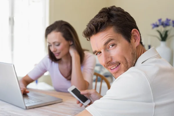 Casal usando laptop e celular em casa — Fotografia de Stock