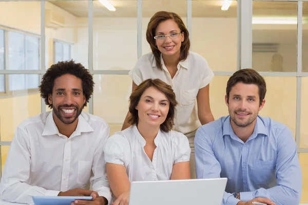 Smiling business people using laptop at office — Stock Photo, Image