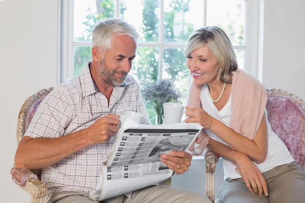 Couple reading newspaper while drinking coffee — Stock Photo, Image