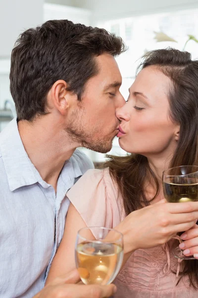 Любящая пара с бокалами вина целуется дома — стоковое фото