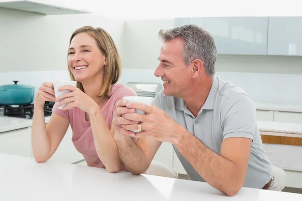 Gelukkige ontspannen paar met koffie kopjes in keuken — Stockfoto