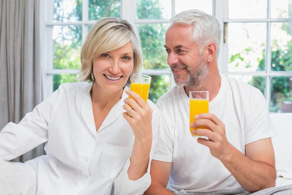 Feliz casal maduro segurando sucos de laranja — Fotografia de Stock