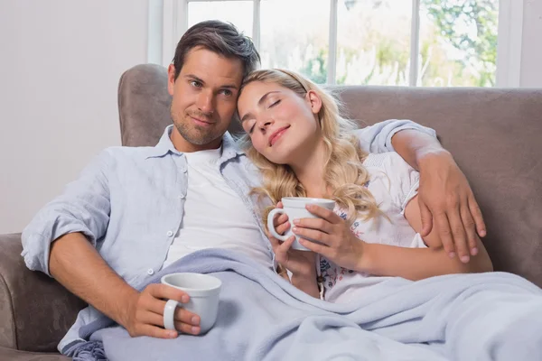 Casal relaxado com xícaras de café sentado no sofá — Fotografia de Stock