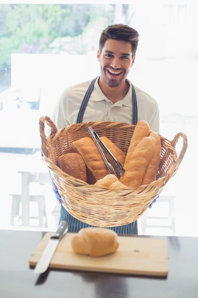 Mutlu genç garson kahve dükkanında kasaya ekmek sepeti ile — Stok fotoğraf