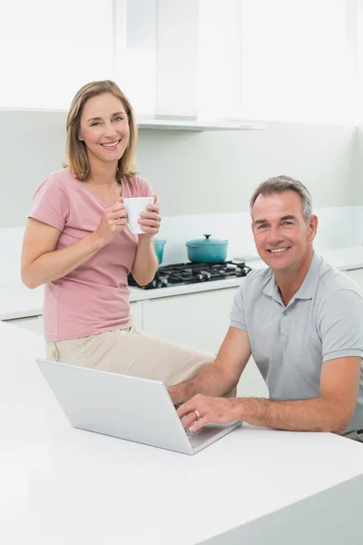 Portrait of a happy couple using laptop in kitchen — Stock Photo, Image