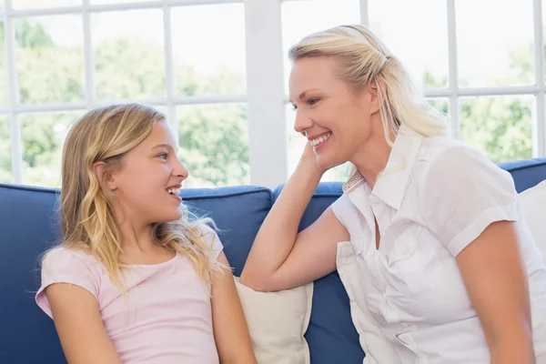 Happy mother and daughter sitting on sofa — Stock Photo, Image