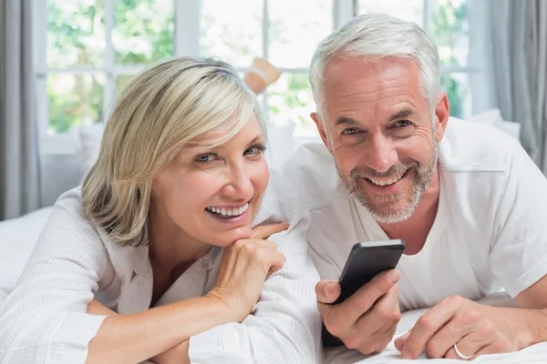 Porträt eines fröhlichen, reifen Paares beim SMS-Lesen — Stockfoto