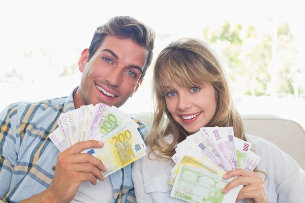 Portrait of a young couple holding fanned out Euro notes — Stock Photo, Image