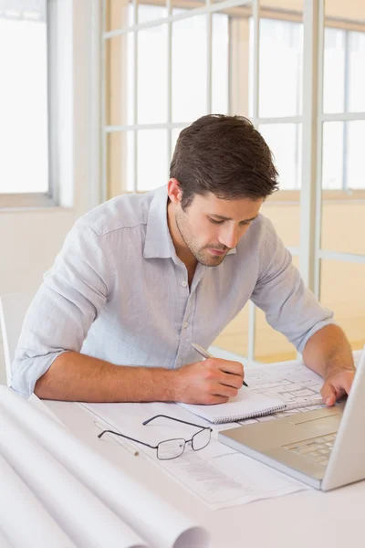 Businessman working on blueprints in office — Stock Photo, Image