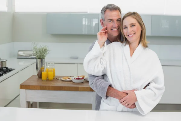 Mann umarmt Frau in Küche von hinten — Stockfoto