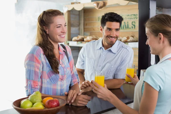 Waitress giving orange juice to a couple at coffee shop — Stock Photo, Image