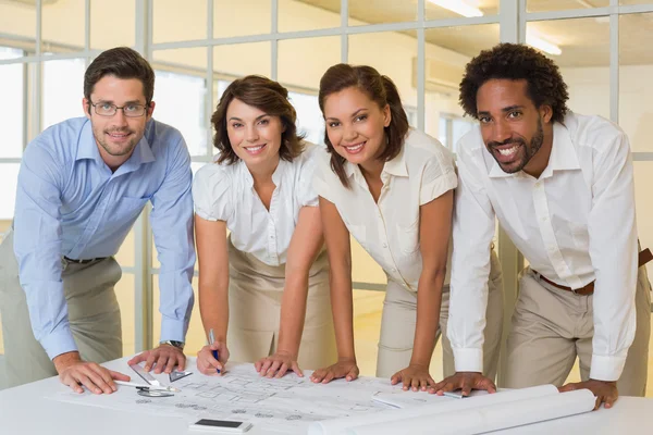 Lachende collega's werken aan blauwdrukken — Stockfoto