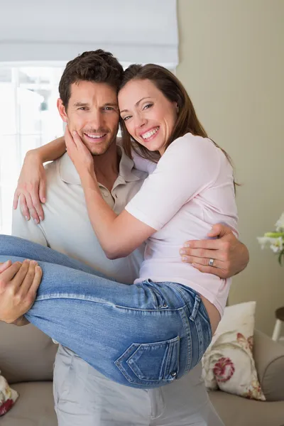 Homme souriant portant femme à la maison — Photo