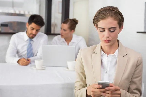 Mensajería de texto de mujer de negocios con colegas en el escritorio de la oficina — Foto de Stock