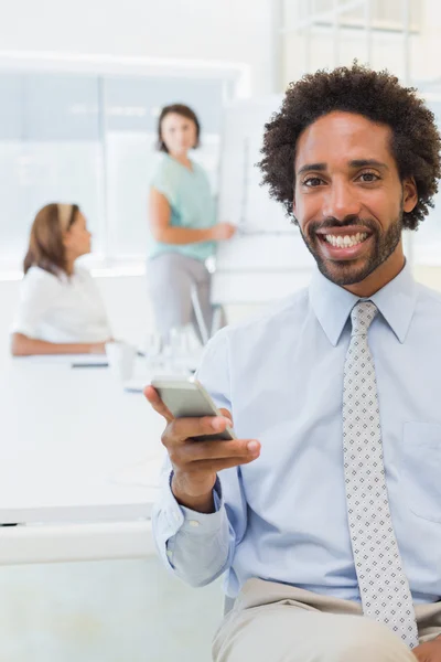 Smiling businessman text messaging with colleagues in office — Stock Photo, Image