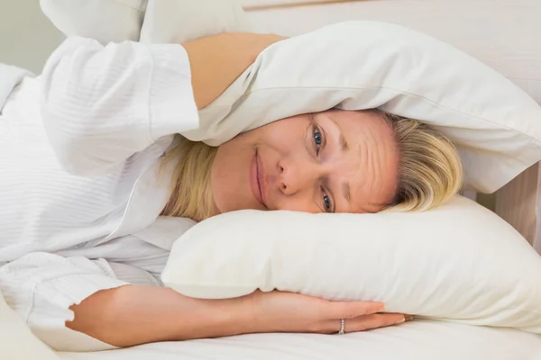 Mujer irritada cubriendo orejas con almohadas — Foto de Stock