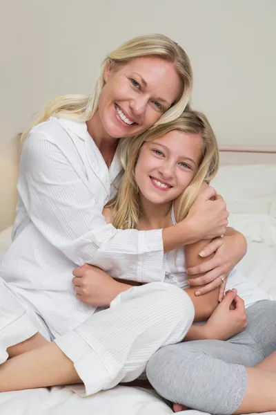 Happy mother hugging cute daughter in bed — Stock Photo, Image