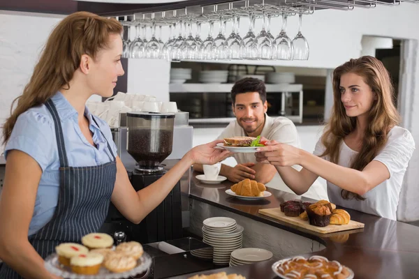 Cafe owner giving sandwich to a woman at coffee shop — Stock Photo, Image