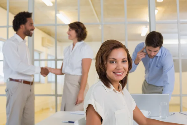 Улыбающаяся деловая женщина с коллегами, пожимающими руки в офисе — стоковое фото