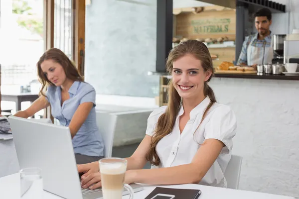 Smiling woman using laptop in coffee shop — Stock Photo, Image