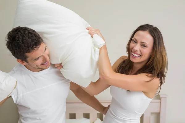 Cheerful couple pillow fighting in bed — Stock Photo, Image