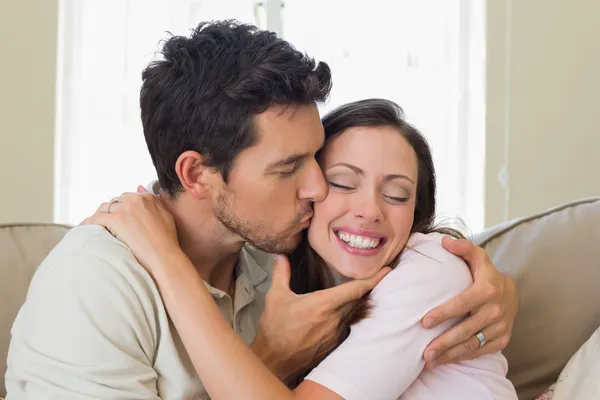 Loving young man kissing woman at home — Stock Photo, Image