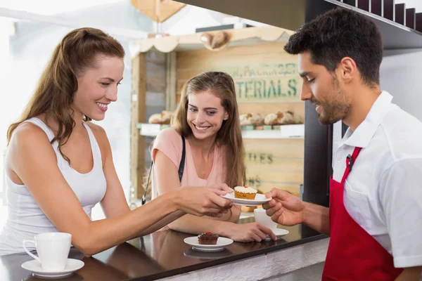 Barista giving pastry to woman at counter in coffee shop — Stock Photo, Image