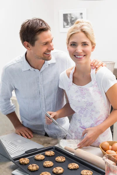 Jovem casal feliz preparando biscoitos na cozinha — Fotografia de Stock