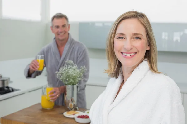 Mulher sorridente e homem com suco de laranja na cozinha — Fotografia de Stock