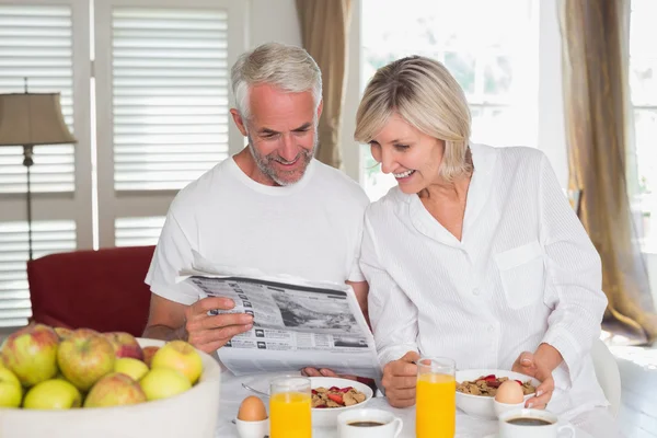 Couple reading newspaper at breakfast table — Stock Photo, Image