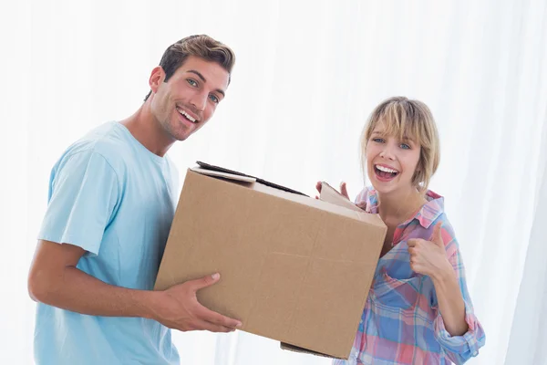 Happy couple carrying cardboard box in new house — Stock Photo, Image