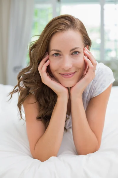 Portret van een mooie lachende jonge vrouw die in bed ligt — Stockfoto