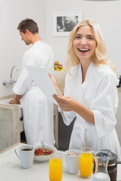 Donna sorridente in possesso di documento con uomo in cucina — Foto Stock