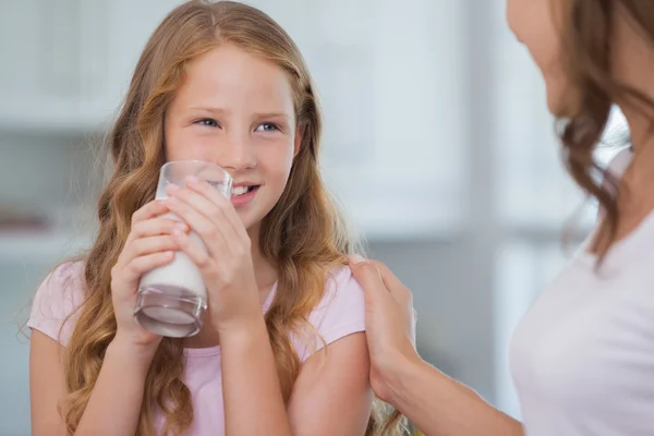 Leuk meisje consumptiemelk als ze naar haar moeder kijkt — Stockfoto