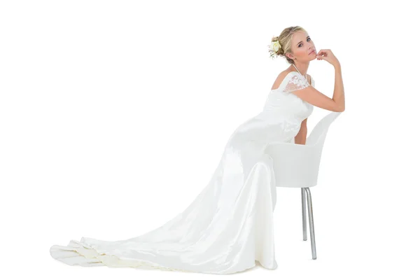 Bride with hand on chin leaning on chair — Stock Photo, Image