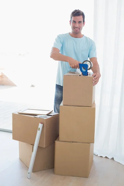 Young man with cardboard boxes in new house — Stock Photo, Image