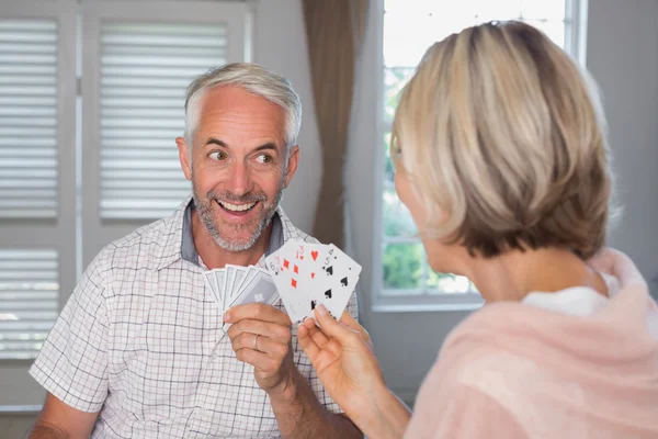 Счастливый зрелый мужчина играет в карты с женщиной дома — стоковое фото