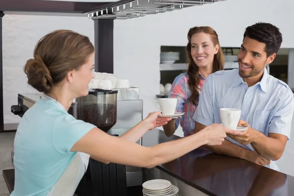 Uśmiechnięta kelnerka dając kawy do kilku w kawiarni — Zdjęcie stockowe