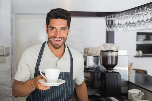 Uśmiechnięty mężczyzna barista gospodarstwa filiżankę kawy w kawiarni — Zdjęcie stockowe