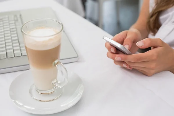 Close-up of drink with hands using mobile phone on table — Stock Photo, Image